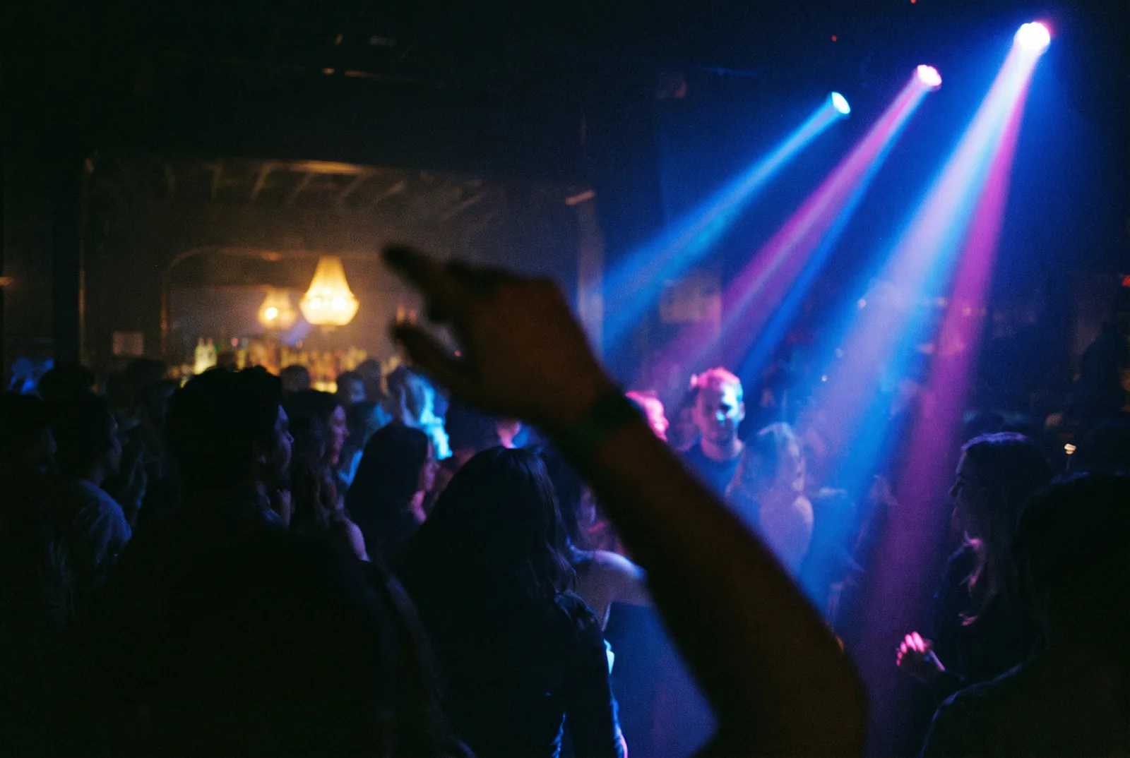 Packed club dance floor under moving-head beams